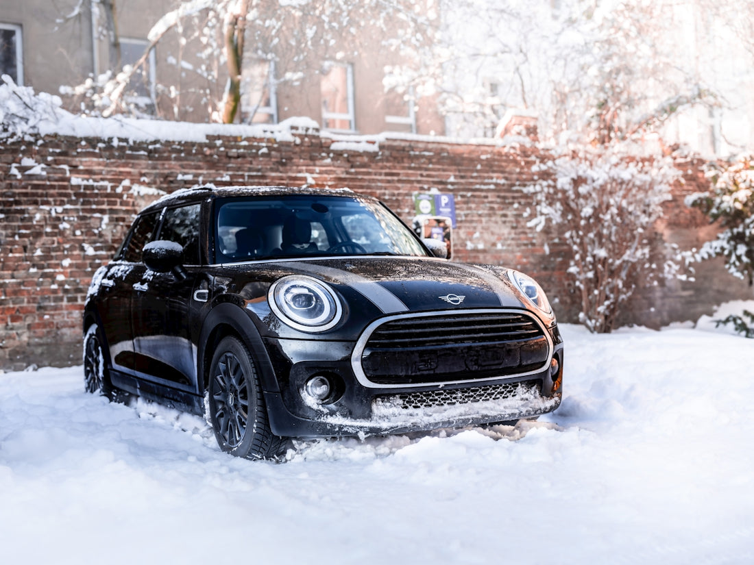 A black mini cooper driving through the snow